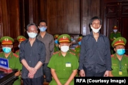 El periodista independiente Nguyen Tuong Thuy (izq), Pham Chi Dung (derecha) y Le Huu Minh Tuan (detrás), durante juicio en Vietnam.