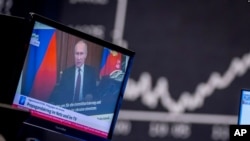 El presidente ruso, Vladimir Putin, aparece en un televisor en la bolsa de valores de Frankfurt, Alemania, el 25 de febrero de 2022, con el titular "Guerra de propaganda en línea y en televisión". 