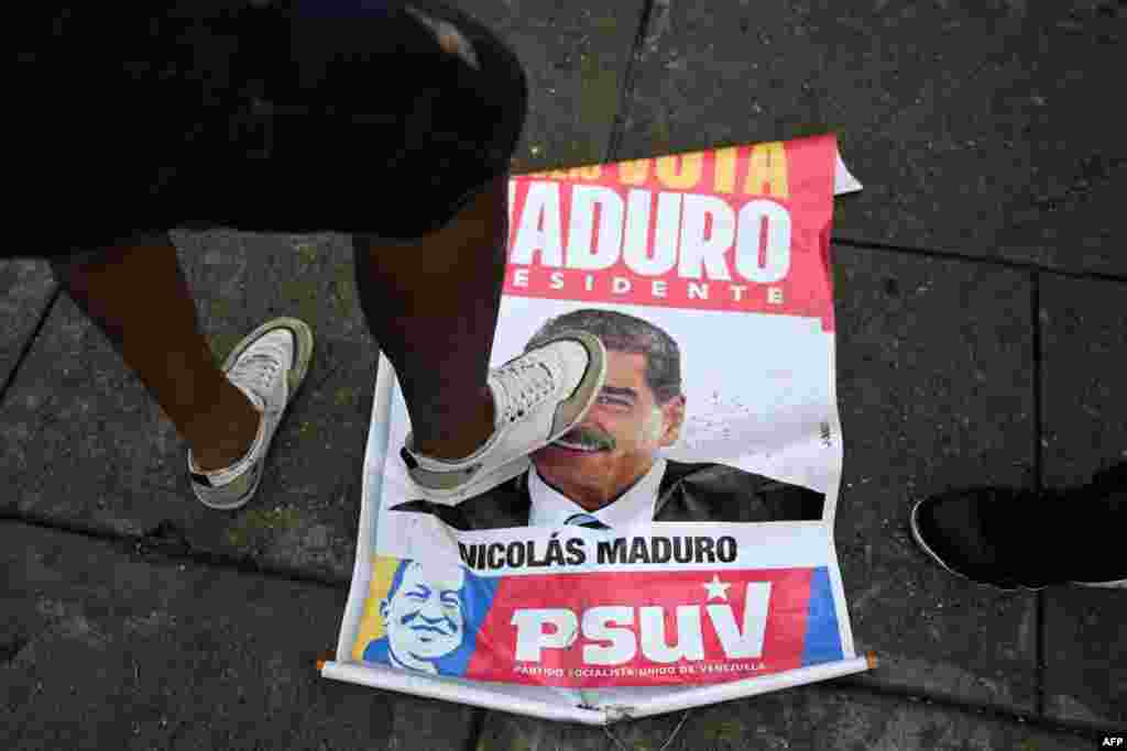 Opositor al Gobierno de Nicolás Maduro pisa un cartel con la imagen del presidnete venezolano durante una protesta el lunes en el barrio de Petare, en Caracas, tras conocerse el resultado oficial de las elecciones que dan al candidato oficialista como ganador.