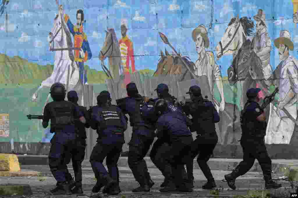 Agentes de policía se cubren de los manifestantes durante contra Nicolás Maduro en Caracas el 29/07/ de julio de 2024 (Foto de Yuri CORTEZ / AFP)