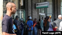 Cubanos hacen cola afuera de un banco. Foto: Yamil Lage (AFP)