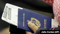 Una persona sostiene su pasaporte cubano antes de subir a un vuelo (Julio Cortez/AP) 