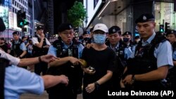 La policía detiene a una mujer en el Parque Victoria, en Hong Kong, en el aniversario 34 de la masacre de Tiananmen. (AP/Louise Delmotte)