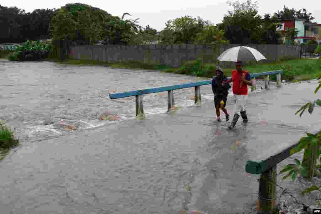 Personas caminan en una calle después de que las fuertes lluvias provocaron una inundación en Camagüey, Cuba