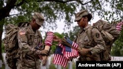 Miembros del Tercer Regimiento de Infantería de Estados Unidos, conocido como La Vieja Guardia, instalan banderas norteamericanas frente a las lápidas del Cementerio Nacional de Arlington, el pasado 25 de mayo de 2023. (AP Photo/Andrew Harnik)