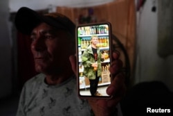 Roberto Sabori, de 53 años, muestra una fotografía sin fecha de su hijo Yasmani comprando en un supermercado en Rusia, en La Federal, Cuba, el 19 de septiembre de 2023. REUTERS/Alexandre Meneghini