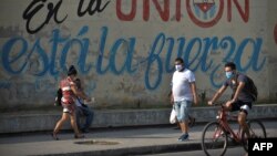 Residentes de La Habana pasan frente a un cartel con propaganda del régimen durante la pandemia de coronavirus, el 13 de abril del 2020.