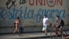 Residentes de La Habana pasan frente a un cartel con propaganda del régimen durante la pandemia de coronavirus, el 13 de abril del 2020.