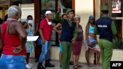 Policías controlan una cola para comprar alimentos en Cuba. YAMIL LAGE / AFP