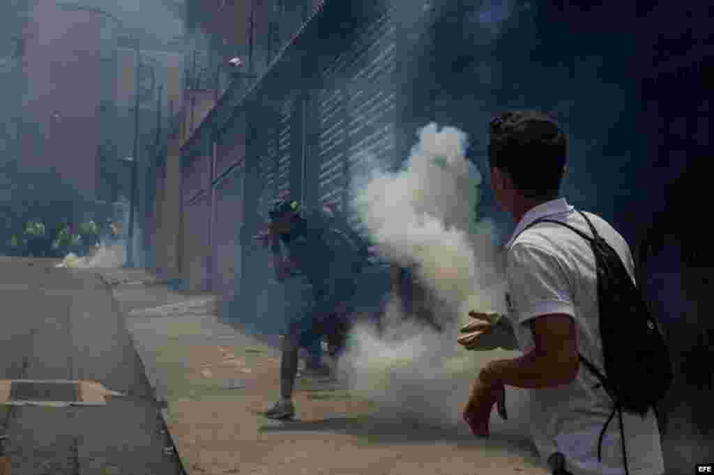  Manifestantes evaden gases lacrimógenos lanzados por miembros de la Policía Nacional Bolivariana (PNB).