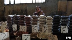 Una mujer vende frijoles en un mercado.
