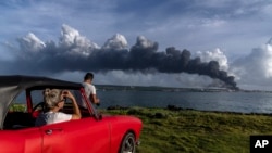 Residentes de zonas cercanas a la base de supertanqueros de Matanzas observan la columna de humo negro que se desprende del incendio. Cerca de 5 mil residentes han sido evacuados. (AP/Ramon Espinosa)