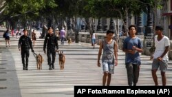 La gente camina en el Paseo del Prado mientras miembros de la policía patrullan en La Habana, Cuba, el lunes 11 de julio de 2022. 