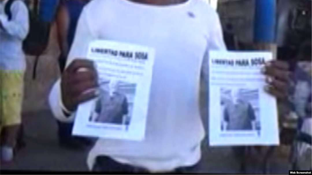 Reporta Cuba. Un activista portando proclamas por la libertad de un preso político.