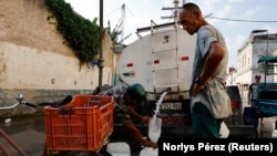 Un cubano llena tanques de agua de una pipa en La Habana. REUTERS/Norlys Pérez