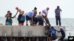 Residentes de la zona ayudan a balseros cubanos cerca de Key West, Florida, el 22 de agosto de 2022. (AP Photo/Mary Martin).