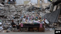 Un comerciante en su puesto de ventas de cosméticos y productos para el hogar, frente a un edificio destruido en la ciudad de Gaza, el 31 de agosto de 2026.