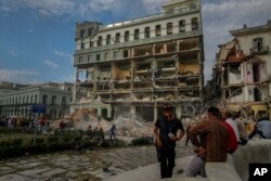 Personas observando los trabajos de rescate luego de una explosión letal que dañó el hotel Saratoga, en La Habana, el viernes 6 de mayo de 2022. (AP Foto/Ramón Espinosa)