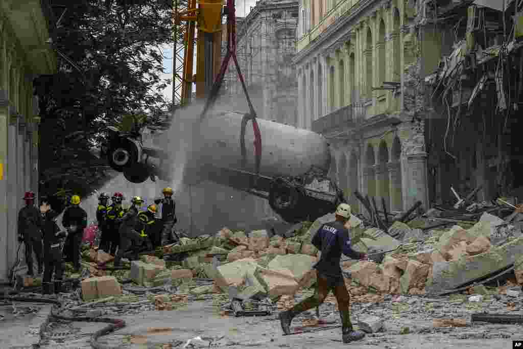 Los bomberos roc&#237;an con agua un cami&#243;n cisterna para enfriarlo mientras lo retiran del lugar de una explosi&#243;n letal que da&#241;&#243; el hotel Saratoga en La Habana, el viernes 6 de mayo de 2022. (AP Foto/Ram&#243;n Espinosa)