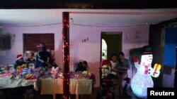 Personas venden productos en el porche de una casa con adornos navideños durante la peregrinación anual de San Lázaro en Rincón, Cuba, 16 de diciembre de 2023. REUTERS/Alexandre Meneghini
