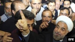 El candidato presidencial Hasan Rohani (d) muestra el dedo manchado de tinta tras ejercer su derecho al voto en la mezquita Imam-Reza en Teherán, Irán