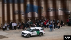 Migrantes y solicitantes de asilo esperan ser procesados ​​por la Patrulla Fronteriza en la frontera entre Estados Unidos y México, vista desde Tijuana, estado de Baja California, México, el 5 de junio de 2024.