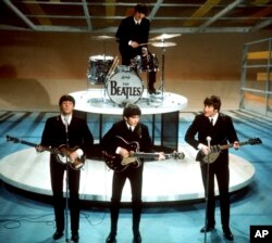 Los Beatles, en primer plano desde la izquierda, Paul McCartney, George Harrison, John Lennon y Ringo Starr en la batería, actúan en el "Ed Sullivan Show" de la CBS en Nueva York el 9 de febrero de 1964. (AP Photo/Archivo)