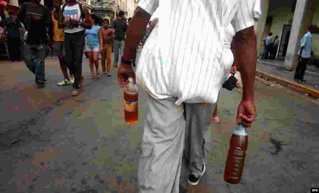 Un hombre camina esta tarde con dos botellas de cerveza por la calle Galiano del municipio Centro Habana, Cuba.