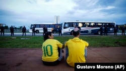 Una pareja de simpatizantes del expresidente Jair Bolsonaro observan el movimiento de agentes de la policía durante una protesta convocada por los partidarios del exmandatario en Brasilia, el miércoles 11 de enero de 2023. (AP Foto/Gustavo Moreno)