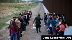 Un grupo de migrantes espera a ser procesado junto al muro fronterizo, en Eagle Pass, Texas. (AP/Dario Lopez-Mills, File)