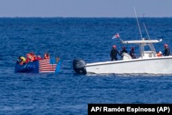 Personas a bordo de una balsa con una bandera estadounidense pintada a un costado son detenidas por la Guardia Costera de Cuba, el 12 de diciembre de 2022.