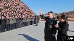 Kim Jong Un y su hija saludan a científicos e ingenieros del régimen norcoreano, que contribuyeron a la prueba de fuego del nuevo misil balístico intercontinental. (Foto: KCNA VIA KNS / AFP).