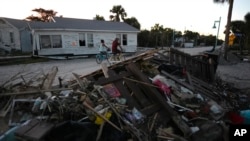 La gente pasa en bicicleta junto a casas dañadas y escombros que dejó el huracán Milton, en Manasota Key, Florida. (Foto AP/Rebecca Blackwell, Archivo)