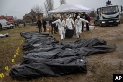 Forenses trasladan el cuerpo de un civil asesinado durante la guerra con Rusia tras sacarlo de una fosa común en Kyiv, Ucrania, el 8 de abril. (AP/Rodrigo Abd)