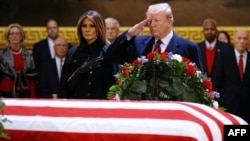El presidente Donald Trump y la primera dama Melania Trump presentan sus respetos frente al féretro del expresidente George H. W. Bush. 