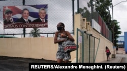 Mujer pasa frente a un cartel con el slogan del gobierno cubano "Somos continuidad". (REUTERS/Alexandre Meneghini)