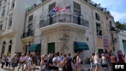 Varios turistas caminan junto a un edificio con las banderas de Cuba y Estados Unidos, en La Habana.