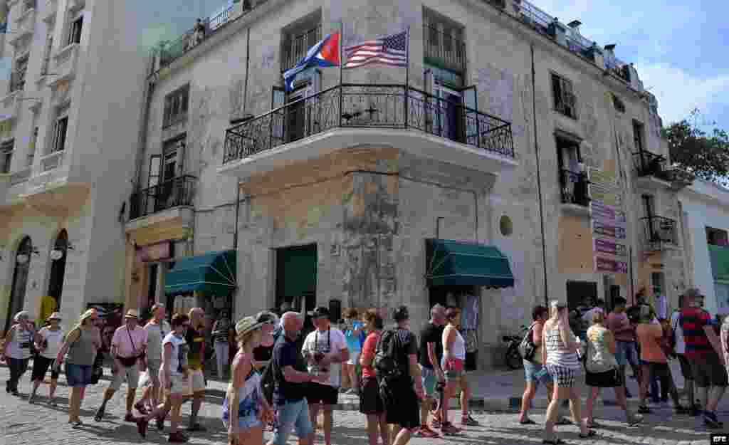 Varios turistas caminan junto a un edificio con las banderas de Cuba y Estados Unidos hoy, jueves 17 de marzo de 2016.