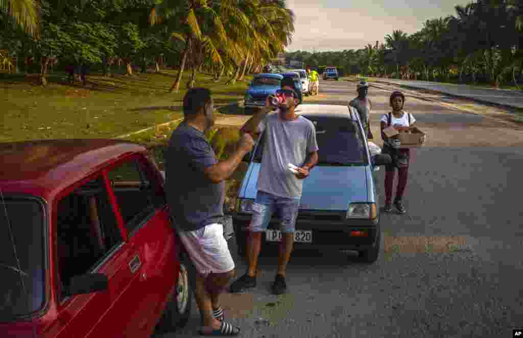 Un conductor bebe un refresco mientras espera que llegue un camión cisterna con combustible, en La Habana, Cuba, el viernes 14 de abril de 2023. (Foto AP/ Ramón Espinosa)