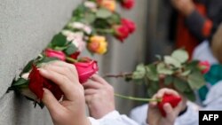 Personas colocan flores en el Memorial del Muro de Berlín el 9 de noviembre de 2023. (Odd ANDERSEN/AFP).