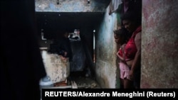 Luzanne de la Castro y su hija en la puerta de su casa examinan los daños del huracán Ian en Pinar del Río. REUTERS/Alexandre Meneghini