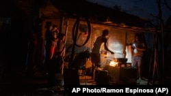 La familia Ramos prepara la cena en el fuego afuera de su casa dañada por el huracán Ian en La Coloma, provincia de Pinar del Río, Cuba, el 5 de octubre de 2022. (AP Foto/Ramón Espinosa)