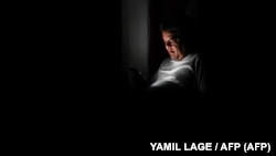 Foto archivo. Un cubano chequea su teléfono durante un apagón. (YAMIL LAGE/AFP).