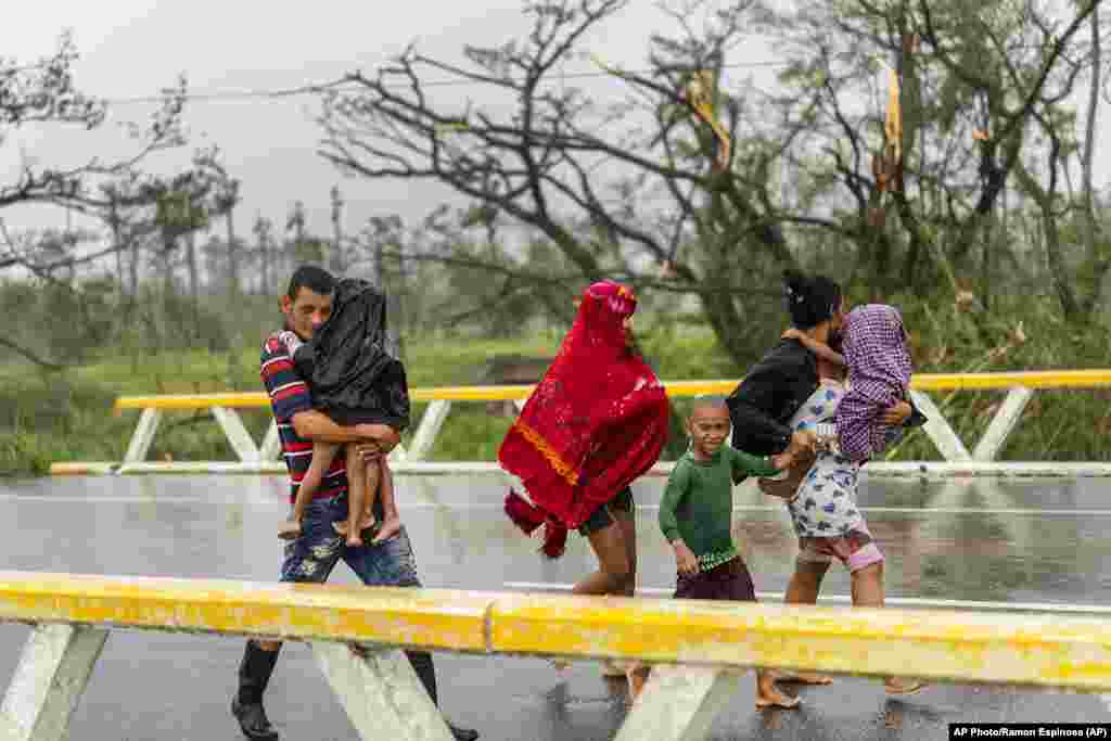 Una familia camina bajo la lluvia en busca de refugio después de que su casa se inundara cuando el huracán Ian azotó Pinar del Río, Cuba, el martes 27 de septiembre de 2022.