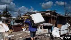 Un residente lleva a cuestas una lavadora dañada después del paso del huracán Ian en La Coloma, provincia de Pinar del Río, Cuba. (AFP/Yamil Lage).
