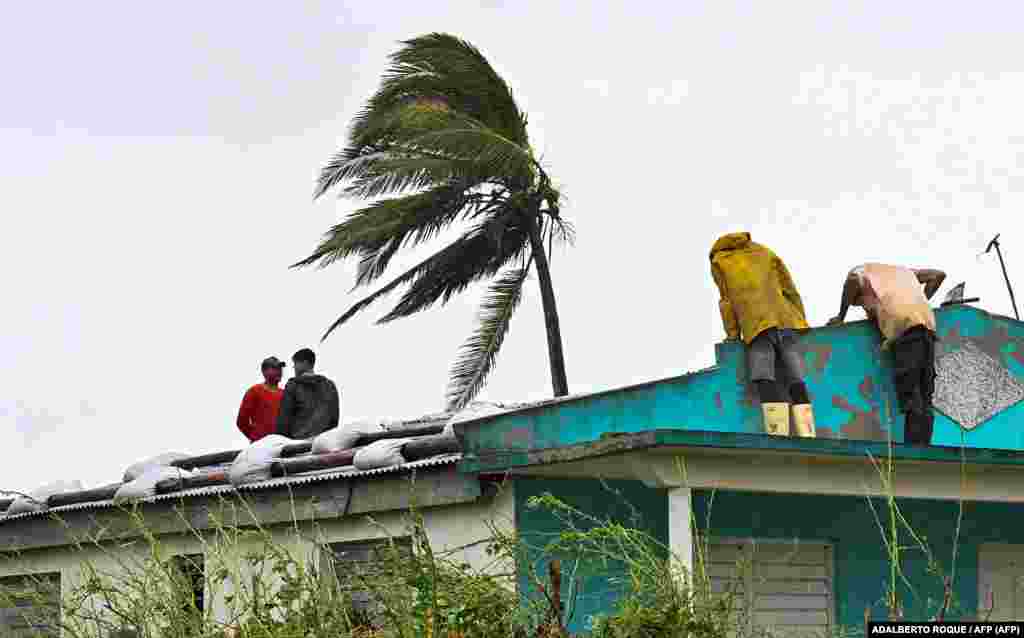 Cubanos reparan un techo en San Juan y Martínez, provincia de Pinar del Río, el 27 de septiembre de 2022 tras el paso del huracán Ian.