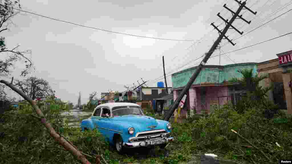 Un automóvil antiguo pasa por los escombros causados ​​por el huracán Ian a su paso en Pinar del Río, Cuba. 