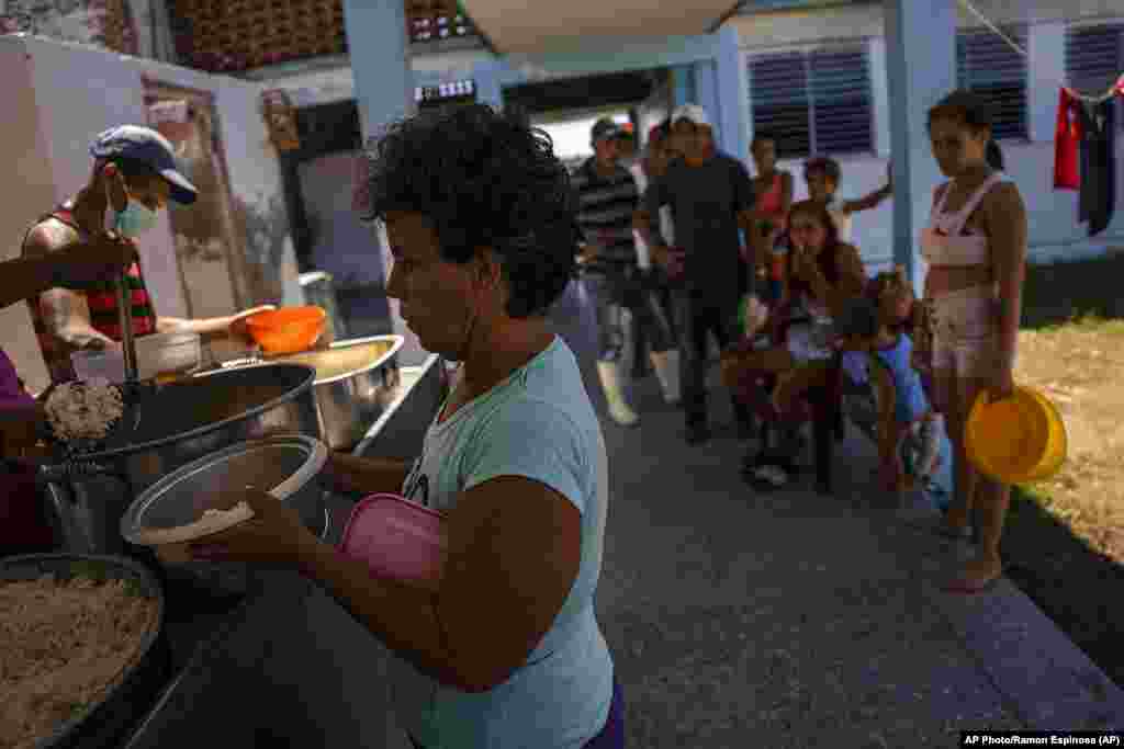 Residentes cuyas casas se volvieron habitables debido al huracán Ian reciben una comida caliente en una escuela convertida en refugio en La Coloma.