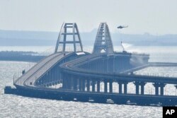 Un helicóptero arroja agua sobre el puente que conecta la península de Crimea con el territorio continental ruso sobre el estrecho de Kerch.
