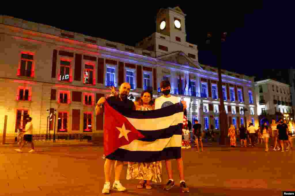 Manifestantes sostiene una bandera cubana mientras los colores de la bandera cubana se proyectan en la fachada de la sede del gobierno regional de Madrid en apoyo a las protestas antigubernamentales en Cuba, en Madrid, España, el 14 de julio de 2021. Foto: REUTERS/Javier Barbancho.
